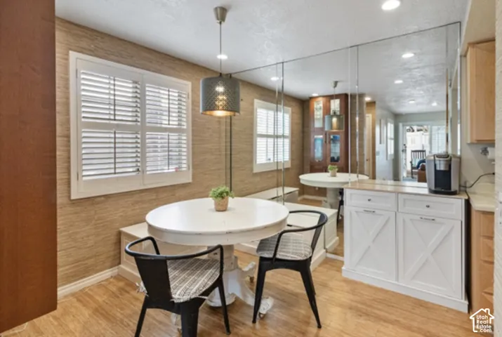 White plantation shutters, wood-finish flooring, full-wall mirrored accent, and built-in white cabinetry with a wood countertop