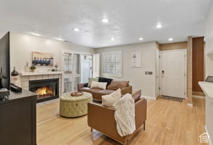Recessed lighting, wood-finish flooring, fireplace with tile surround, white trim, and a paneled entry door