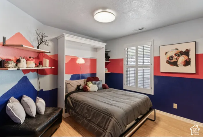 Wood-finish flooring, built-in shelving, window with plantation shutters, and a flush mount ceiling light