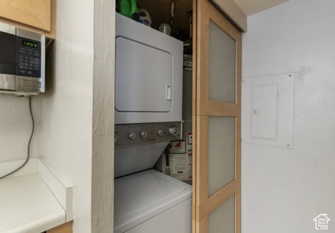 Stackable washer and dryer, wood-finish sliding door with frosted glass panels, built-in microwave, and light-toned countertop