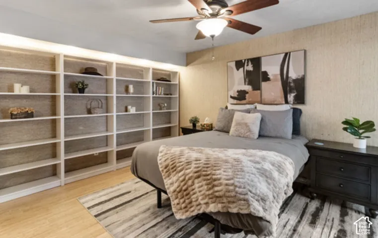 Built-in shelving with overhead lighting, wood-finish flooring, and a ceiling fan with integrated lighting