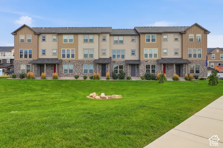 Three-story townhome residences featuring stone veneer, stucco, and vertical siding facades, individual entryways, and a collective green space