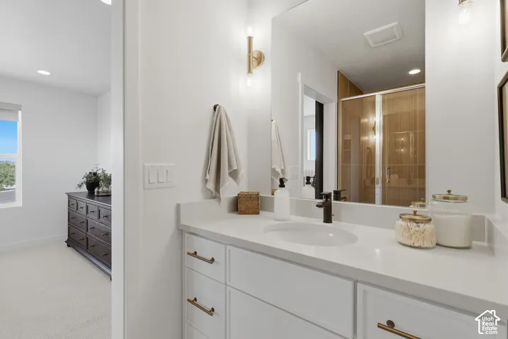 Modern vanity with an integrated sink, matte black faucet, and white cabinetry with gold-finish pulls