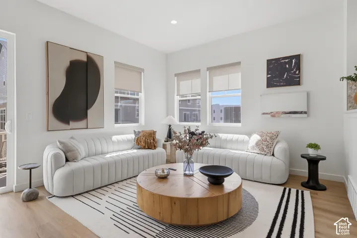 Recessed lighting, light wood-finish flooring, multiple windows, and a glass-paneled door