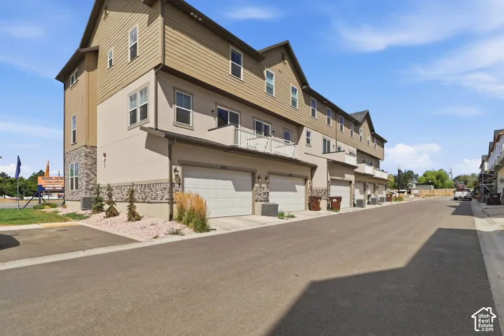 Multi-level residence featuring a stucco and siding exterior, integrated garage, and a balcony