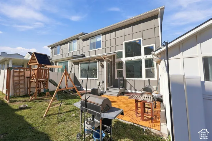 Exterior featuring varied window sizes, a tiled patio, privacy fencing, and a sloped roofline