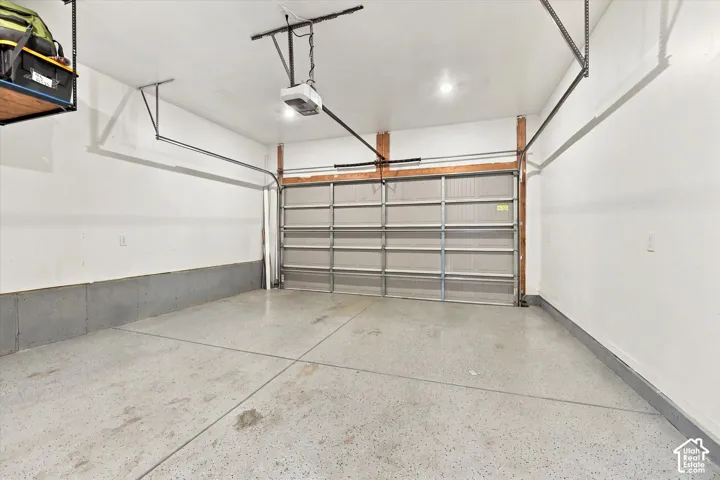 Attached garage with an automated door opener, concrete flooring, and overhead lighting