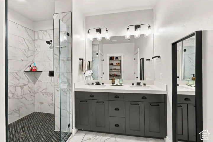 Walk-in shower with clear glass enclosure and black penny tile flooring