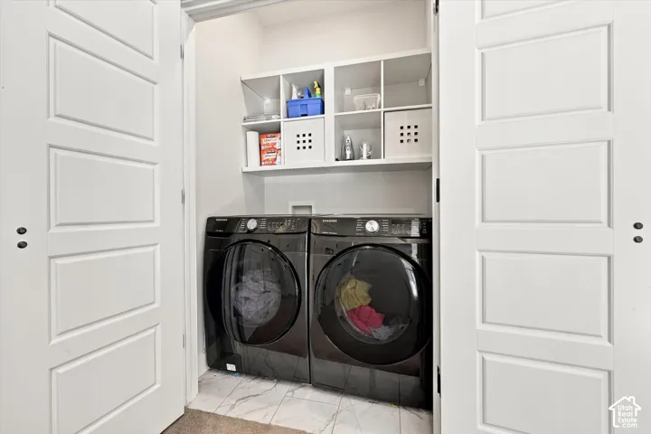 Laundry area with white paneled bifold doors, built-in shelving, a full-size washer, and a full-size dryer