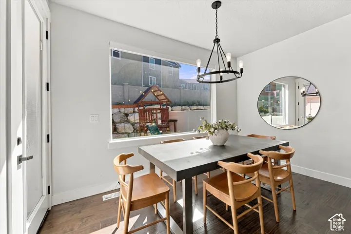 Dining space with wood-finish flooring, a large window, a black metal chandelier, and white wall finishes
