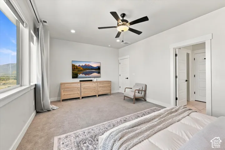 Spacious room with carpeted flooring, large window, ceiling fan, and recessed lighting