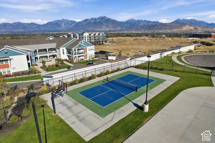 Multi-sport court with basketball hoop and tennis net, surrounded by manicured lawns and concrete pathways