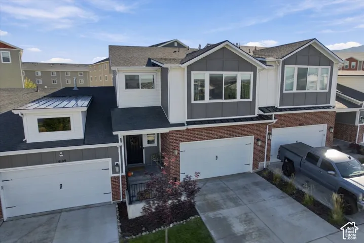 Two-story residence featuring a brick facade, white siding, and gray paneling