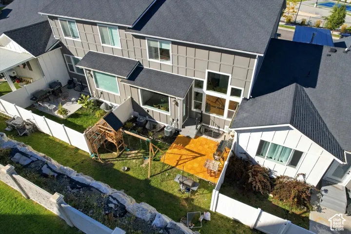 Expansive backyard featuring a manicured lawn, paved patio, concrete patio, and white privacy fencing