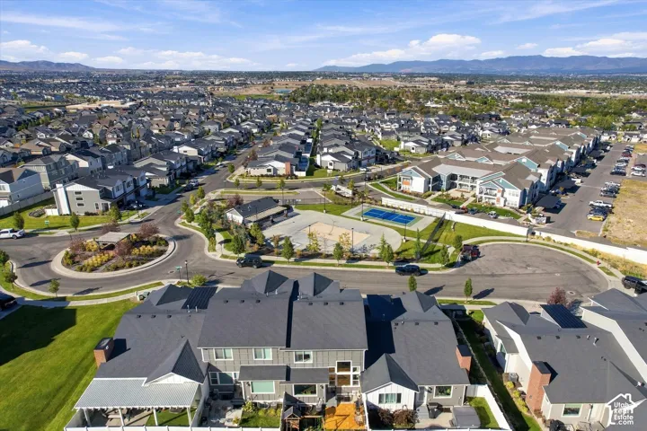 Expansive residential development with mountain backdrop, featuring a communal swimming pool, sport court, and landscaped roundabout