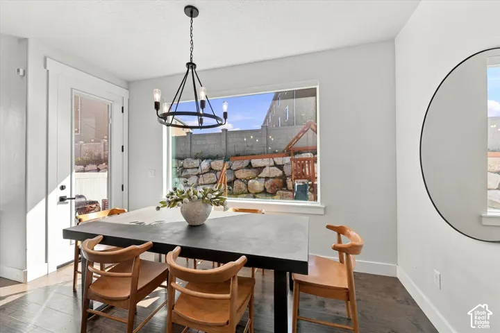 Dark wood-finish flooring, a contemporary black chandelier, and a large picture window