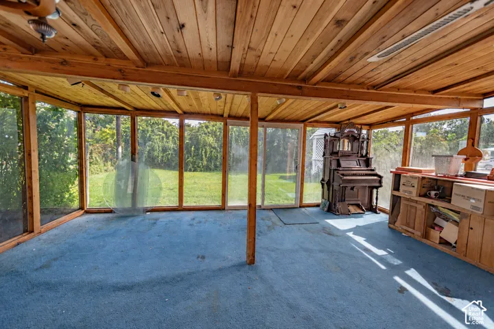 Room featuring a wood-panel ceiling, extensive window walls, blue carpeting, and wood-framed glass sliding doors