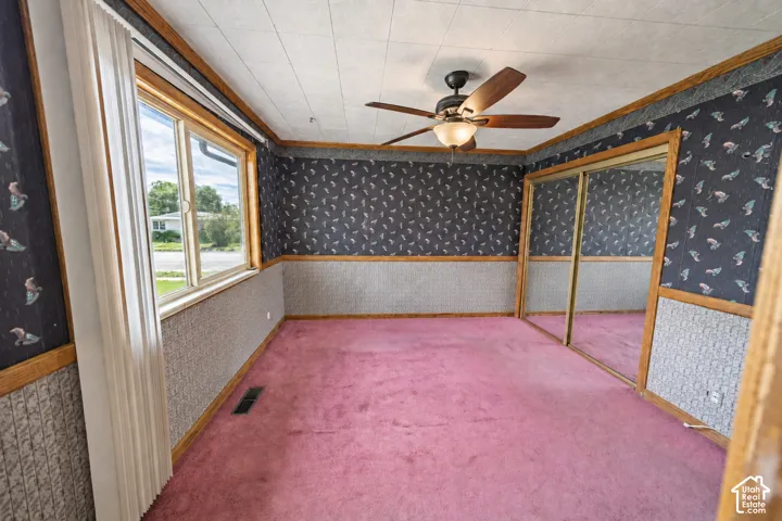 Room featuring a ceiling fan with integrated lighting, wood-trim window, and mirrored sliding closet doors