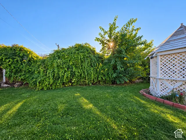 Manicured lawn with a white lattice gazebo, mature trees, and dense perimeter foliage