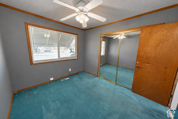 Room featuring a ceiling fan with integrated lighting, a window with horizontal blinds, and a mirrored closet door