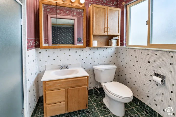 Frosted glass shower enclosure, wood-finish vanity with integrated sink, wood-finish medicine cabinet, wood-finish wall-mounted cabinet, and a toilet