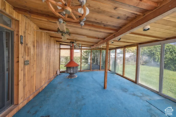 Enclosed patio featuring wood-paneled walls, a wood-plank ceiling, and a freestanding fireplace