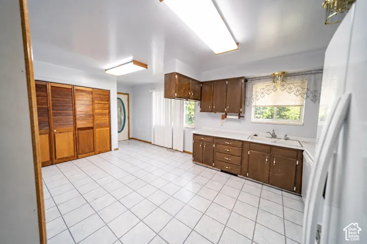 Tile flooring throughout, wood-finish cabinetry, double-basin sink, and built-in closet with louvered doors