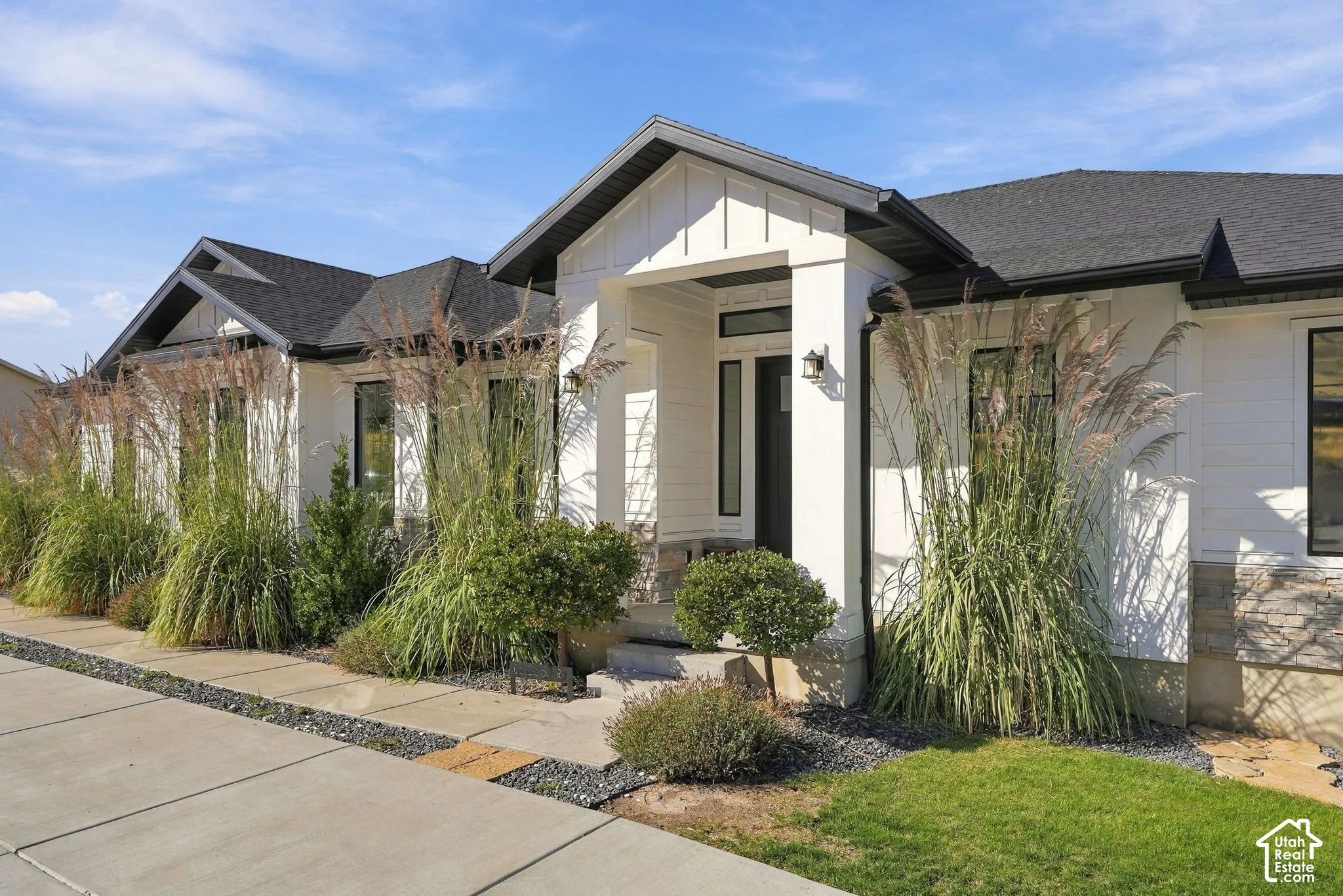 Modern exterior featuring white siding, black-framed windows, and a black shingled roof