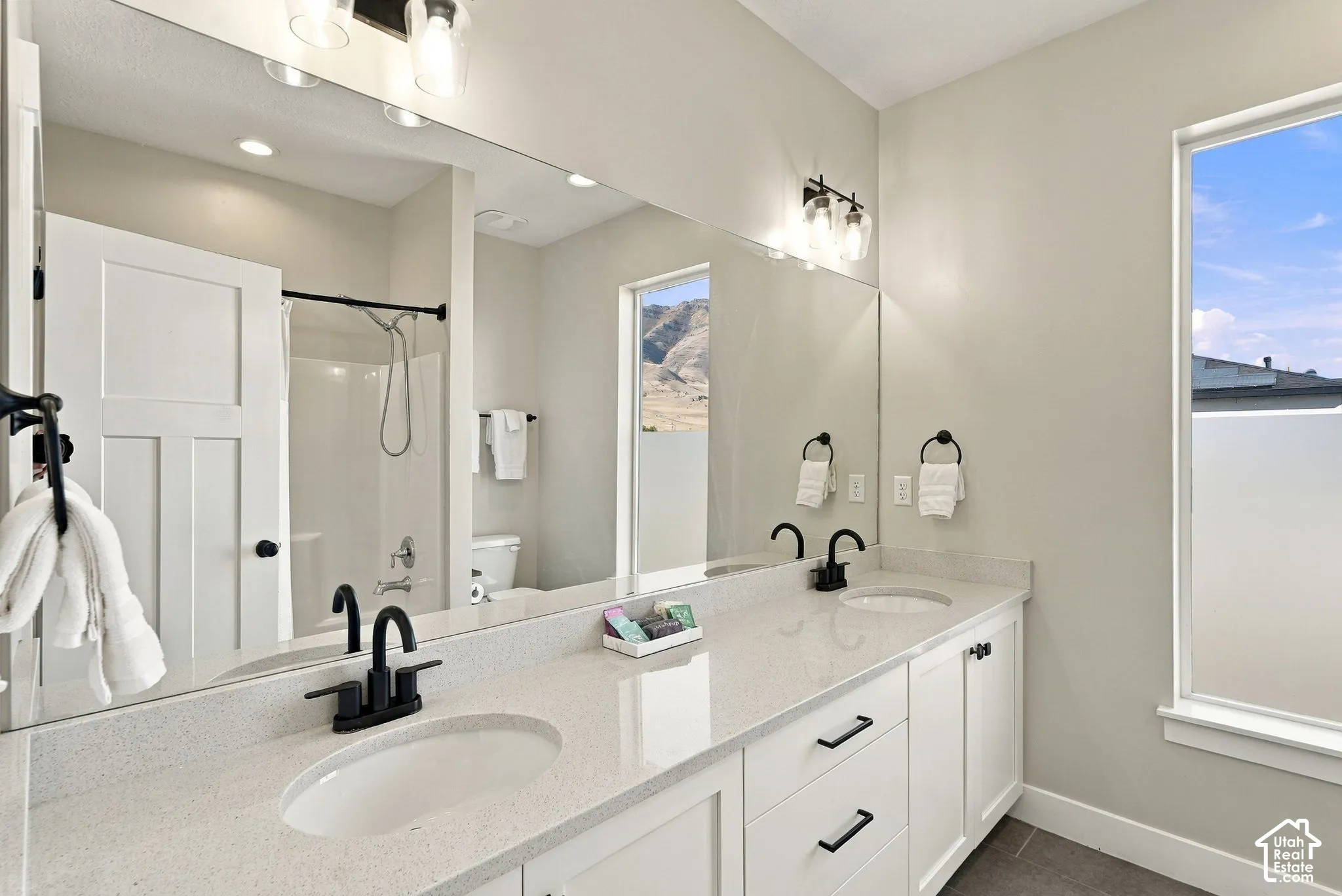 Double vanity with white cabinetry, a light-toned countertop, and matte black fixtures