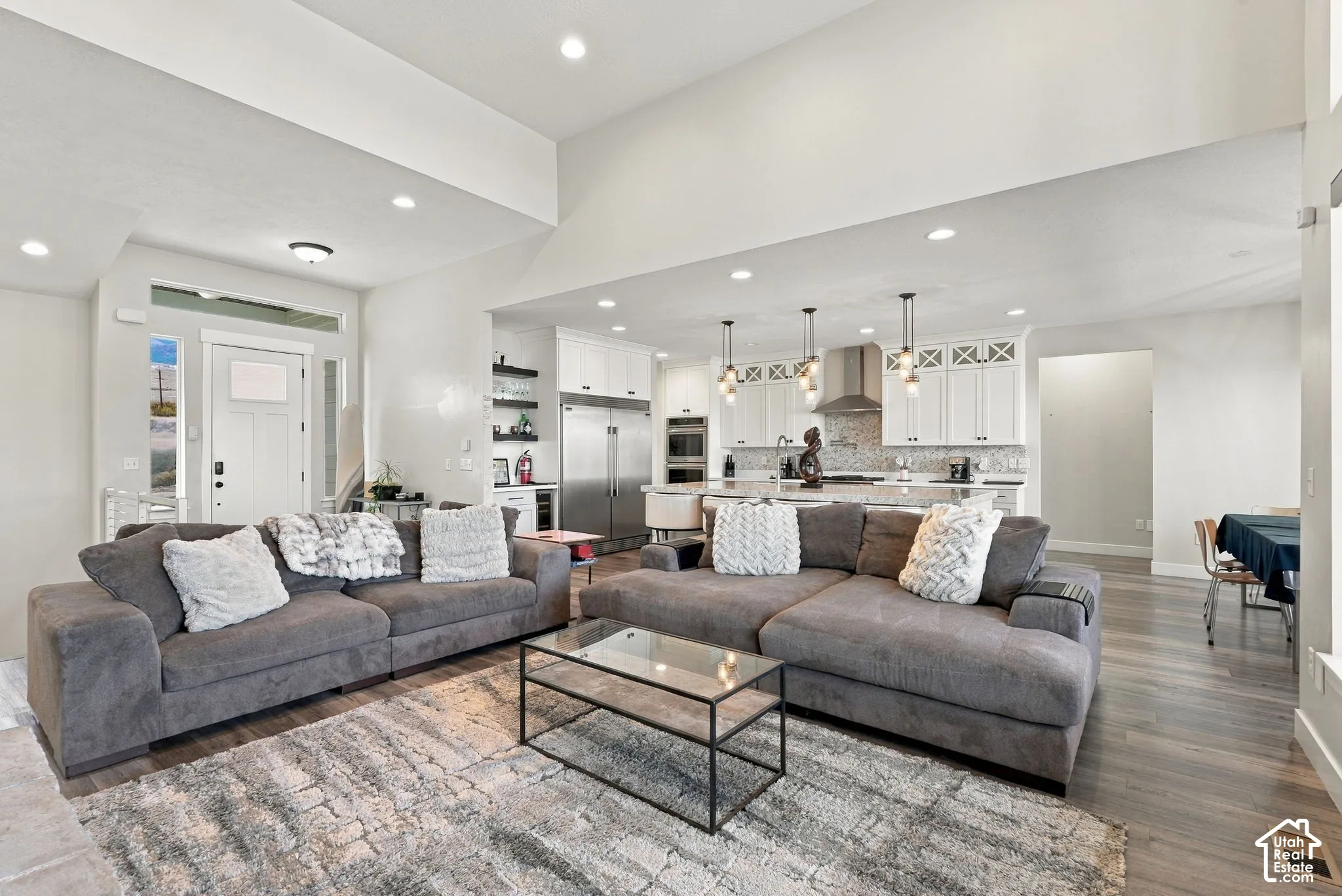 Open-concept living area with vaulted ceilings, recessed lighting, and wood-finish flooring