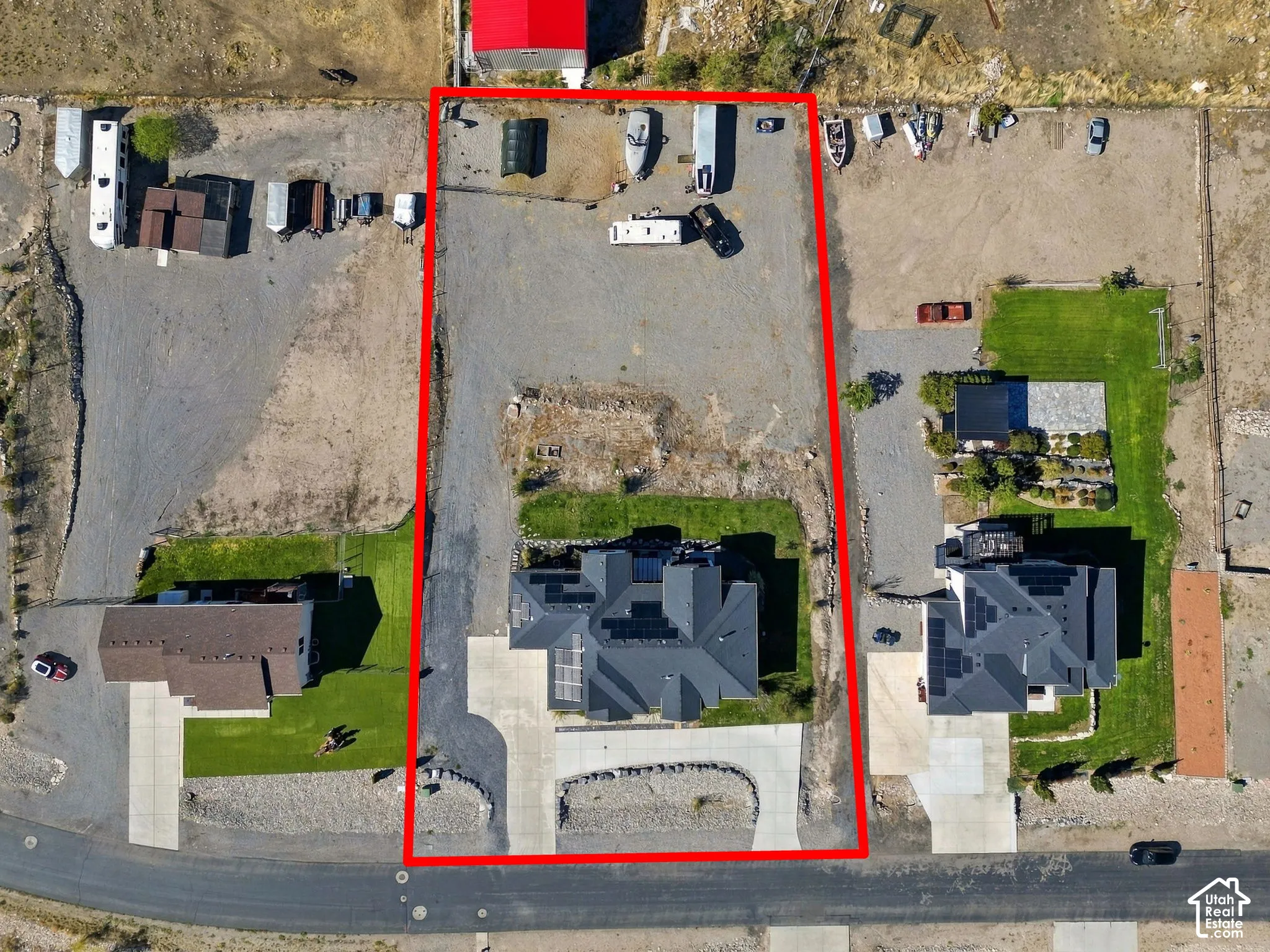Expansive lot featuring a large gravel area, paved driveway, and established landscaping