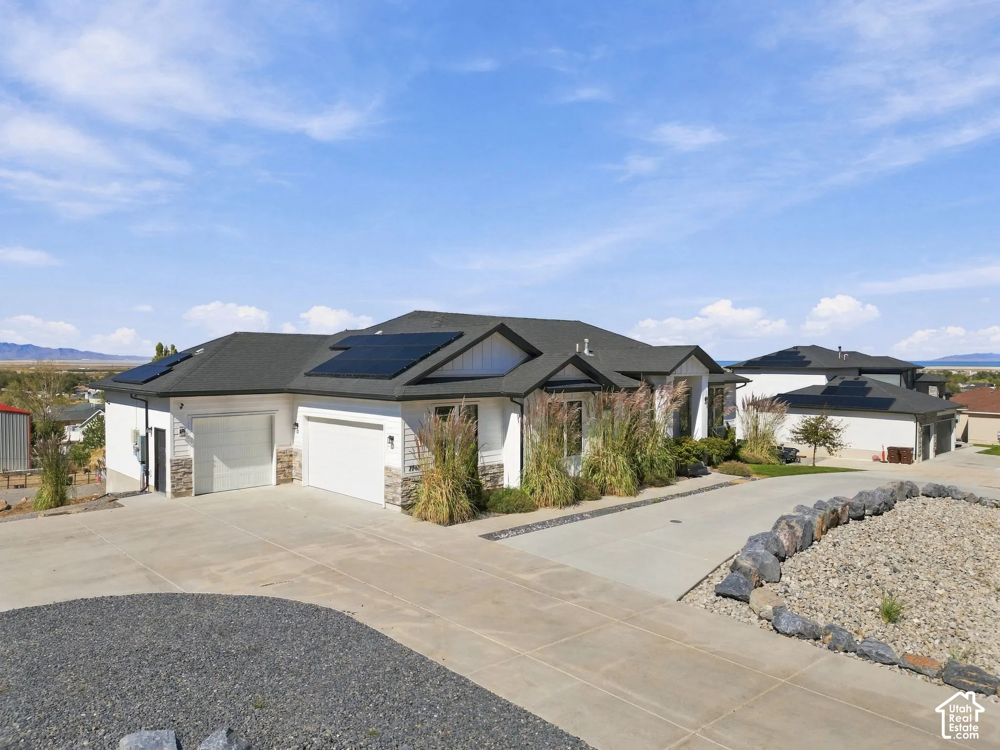 Contemporary residence featuring a dark shingle roof, solar panel array, and a multi-car garage