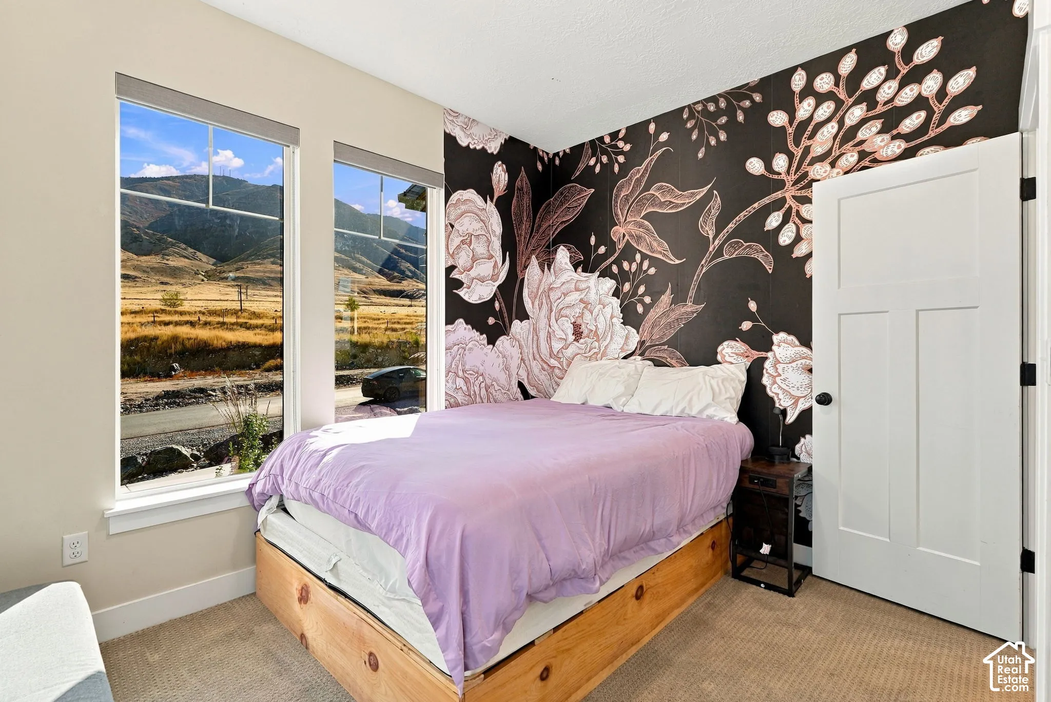 Dual vertical windows, floral accent wall, and a three-panel interior door