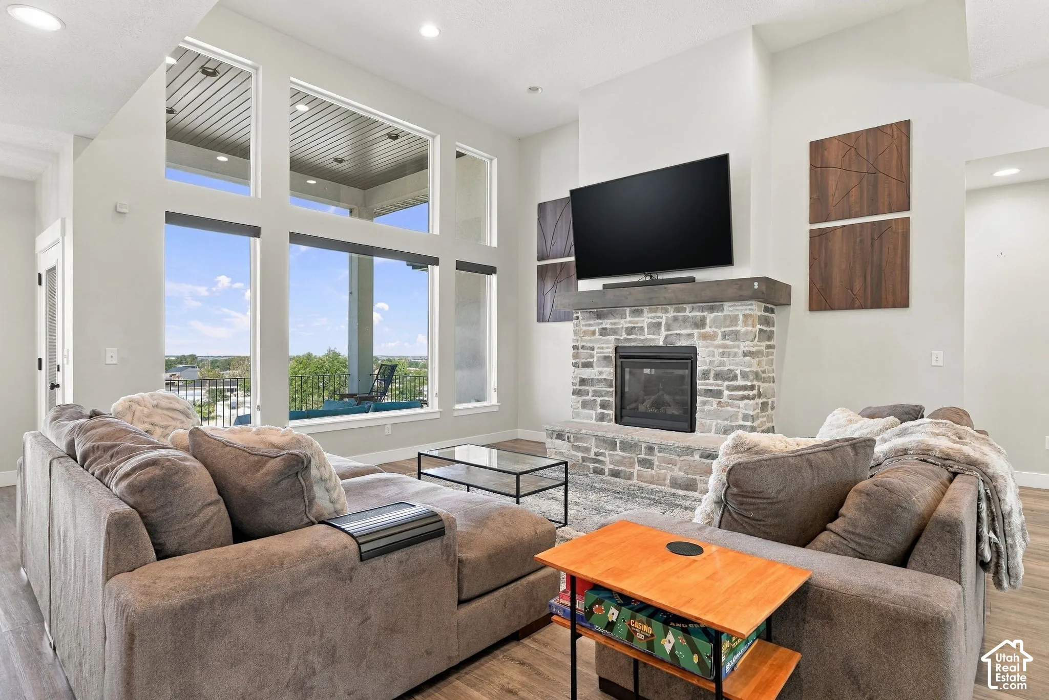 Vaulted ceiling great room with a stone-clad fireplace featuring a dark wood mantel