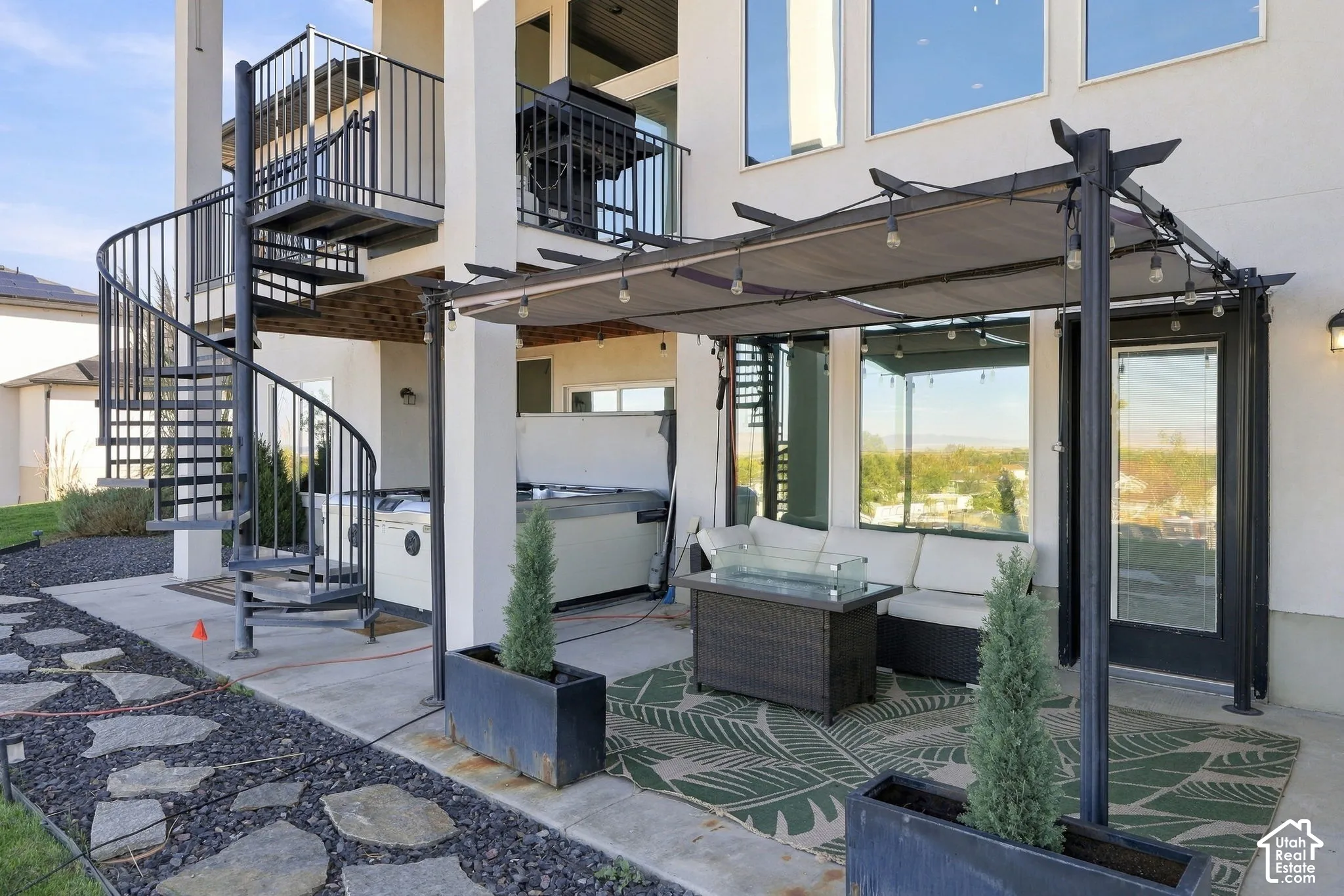 Ground-level patio with a hot tub, a pergola, and large glass doors