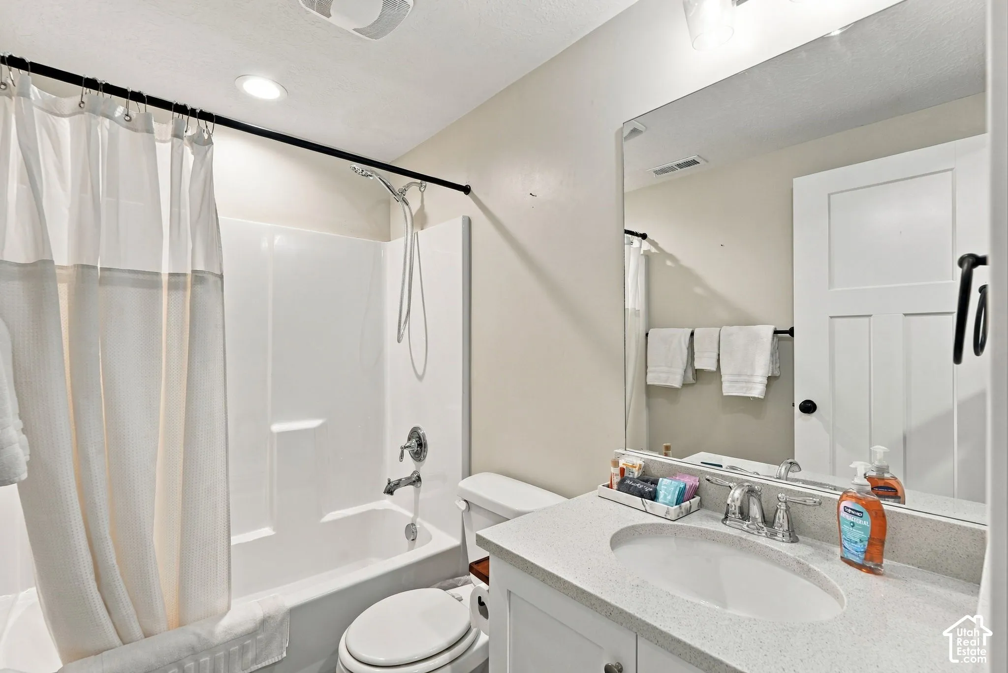 White vanity with a light-toned countertop, oval undermount sink, and chrome-finish faucet