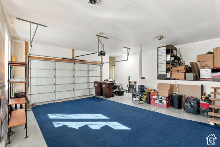 Attached garage with a sectional garage door, overhead garage door opener, and interior lighting