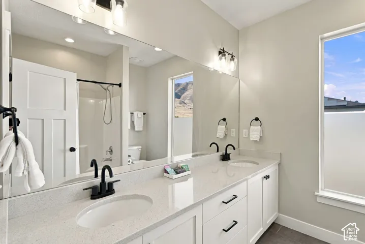 Double vanity with white cabinetry, a light-toned countertop, and matte black fixtures
