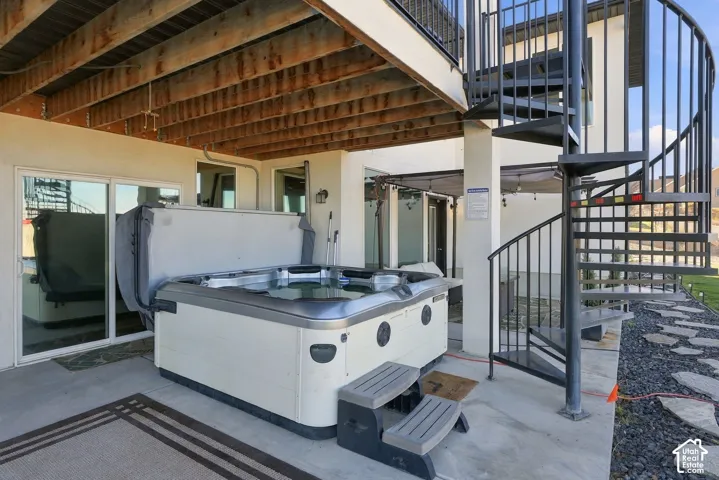 Concrete patio featuring a hot tub, spiral staircase, and sliding glass doors