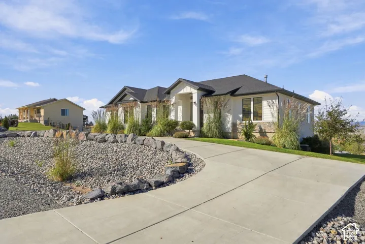 Concrete driveway with a gravel and rock border, leading to a residence featuring horizontal siding, stone accents, and a dark shingle roof