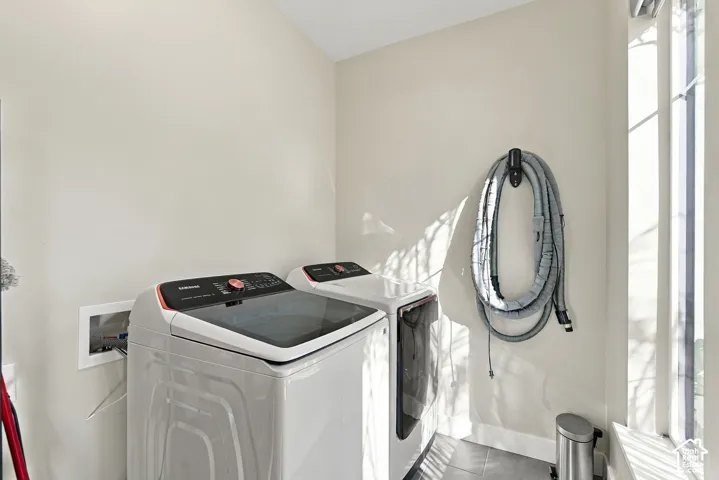 Laundry area featuring a large window, light-toned walls, and tile flooring