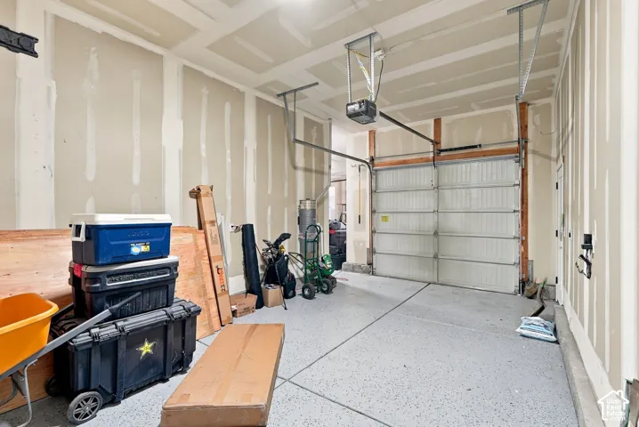 Attached garage with a sectional overhead door, exposed drywall, and a textured concrete floor