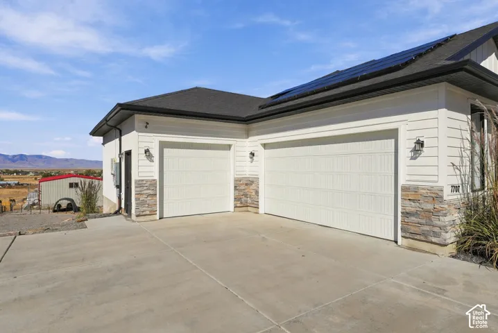 Two-car garage with white paneled doors, complemented by a stacked stone facade and horizontal siding