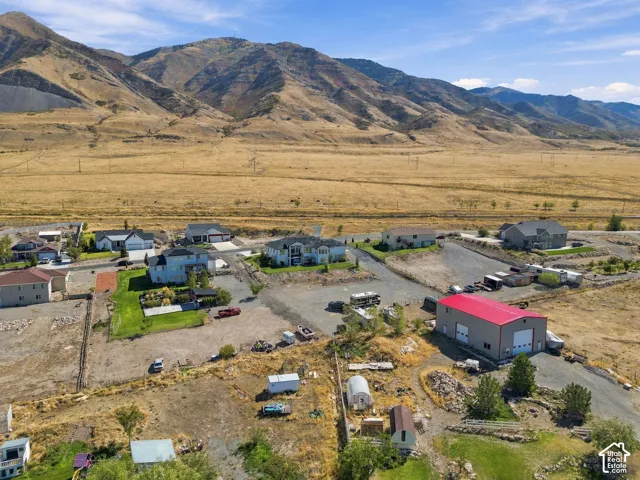 Expansive property featuring a large red-roofed outbuilding, multiple structures, and surrounding mountainous terrain