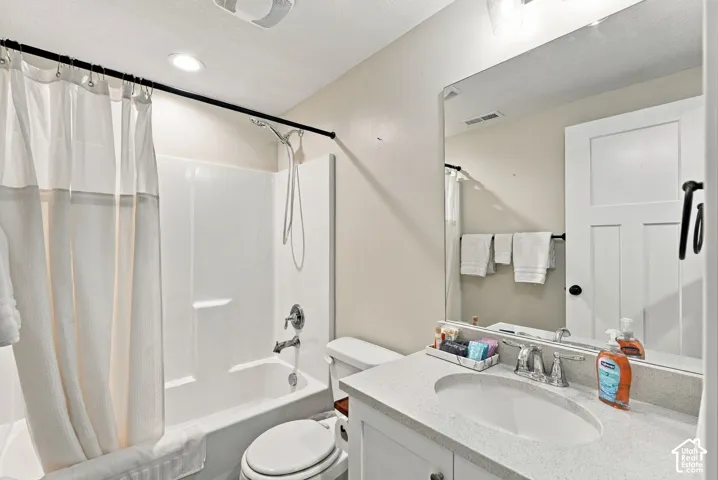 White vanity with a light-toned countertop, oval undermount sink, and chrome-finish faucet