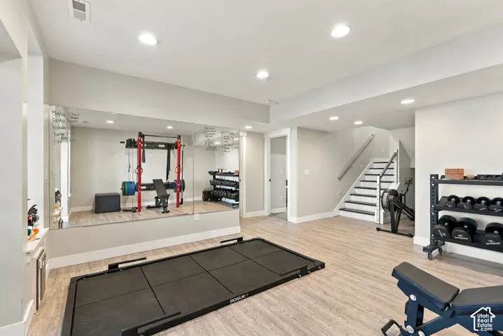 Expansive lower level with recessed lighting, wood-finish flooring, and built-in wall mirrors