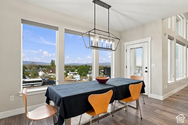Open concept dining area featuring large picture windows, wood-finish flooring, a modern geometric chandelier, and white trim throughout