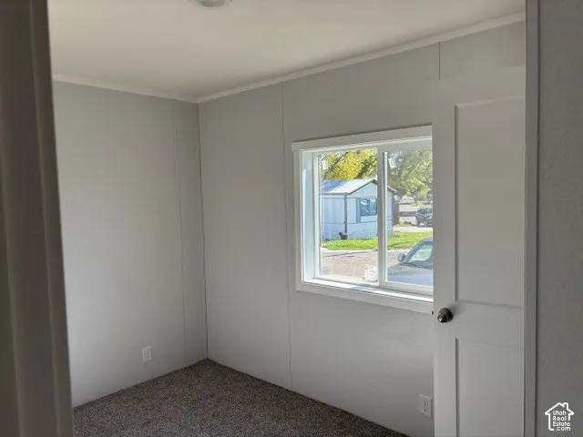 Recessed lighting, light gray panel walls, white trim, and a window with white casing