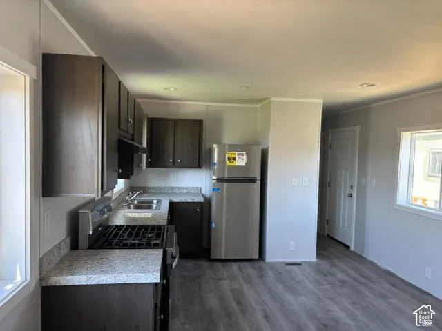Kitchen featuring dark wood-finish cabinetry, light-toned countertops, stainless steel appliances, and wood-finish flooring