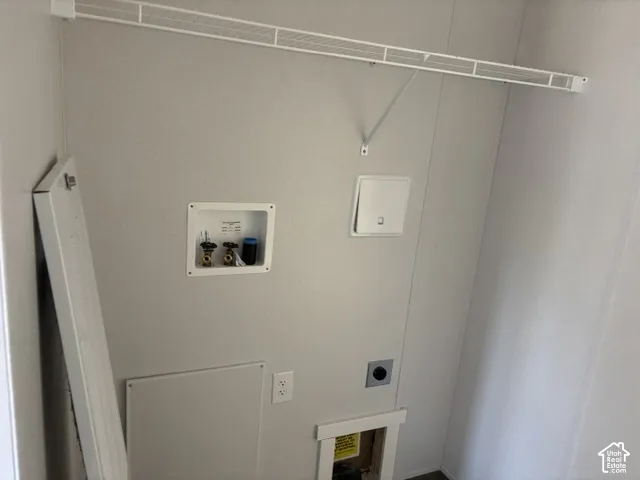 Laundry area featuring a white wire shelving unit, utility hookups, and wall paneling